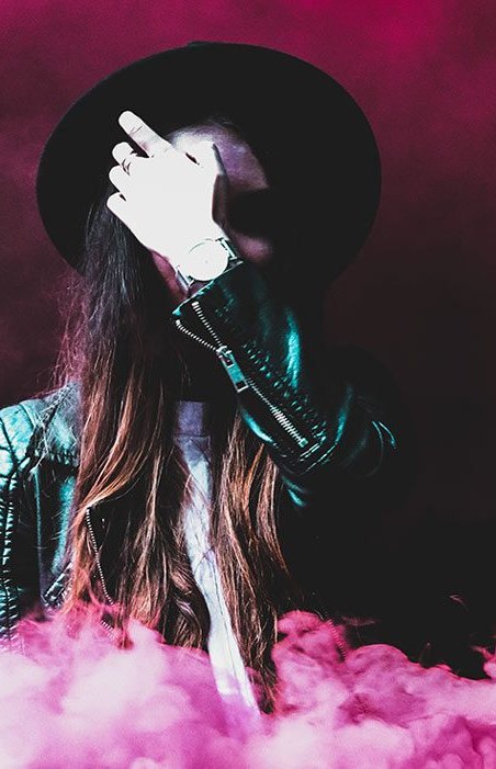 Performer in a hat surrounded by pink smoke